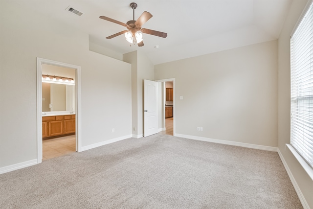 unfurnished bedroom with light carpet, multiple windows, ceiling fan, and ensuite bathroom