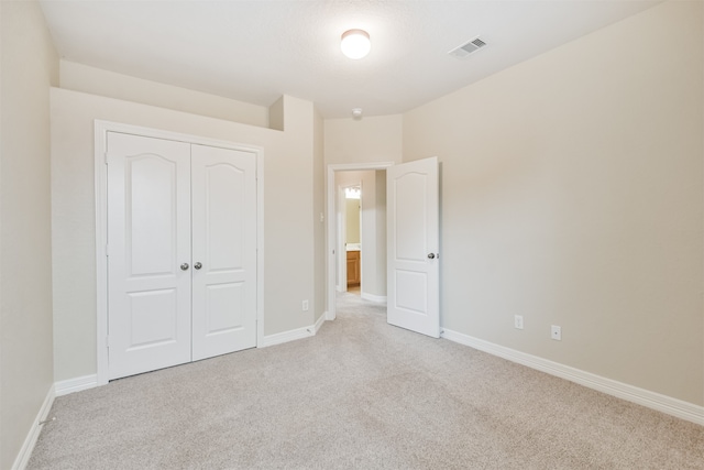 unfurnished bedroom featuring light carpet and a closet