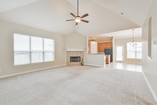 unfurnished living room with light carpet, high vaulted ceiling, a tile fireplace, and ceiling fan with notable chandelier