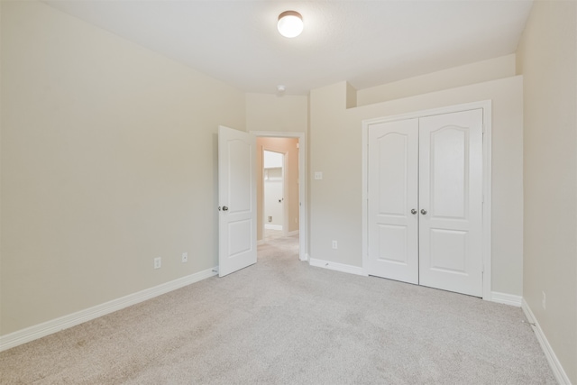 unfurnished bedroom with light carpet and a closet