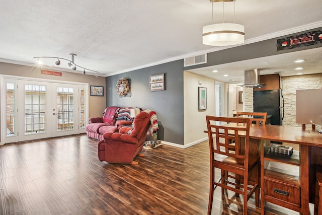 living room featuring rail lighting, hardwood / wood-style flooring, french doors, a textured ceiling, and crown molding