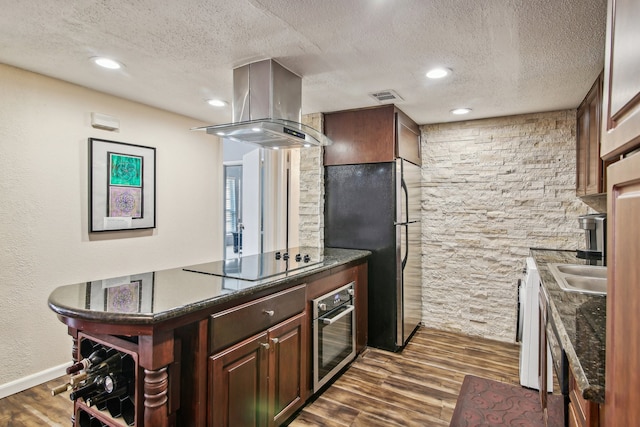 kitchen featuring a textured ceiling, island range hood, dark hardwood / wood-style flooring, and black appliances