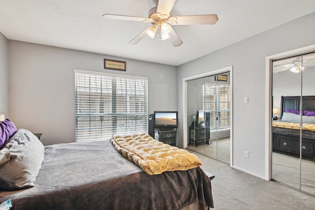 carpeted bedroom featuring multiple windows, two closets, and ceiling fan