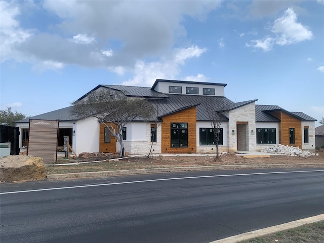 modern home featuring metal roof, stone siding, and a standing seam roof