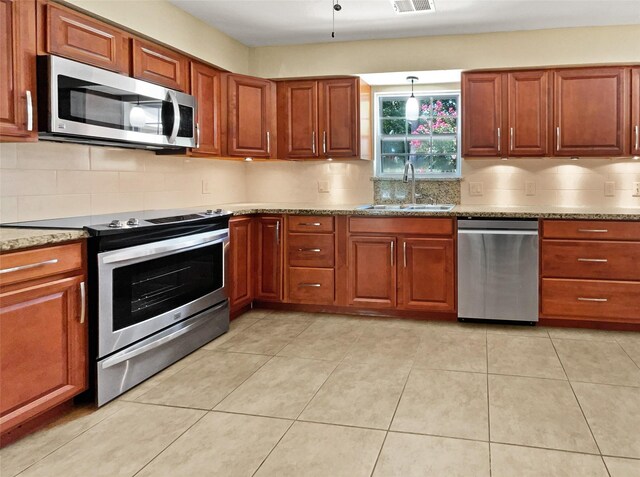 kitchen with tasteful backsplash, stainless steel appliances, sink, pendant lighting, and light tile patterned floors