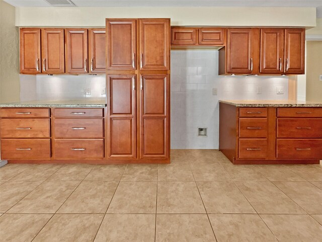 kitchen featuring light tile patterned floors, decorative backsplash, and light stone countertops