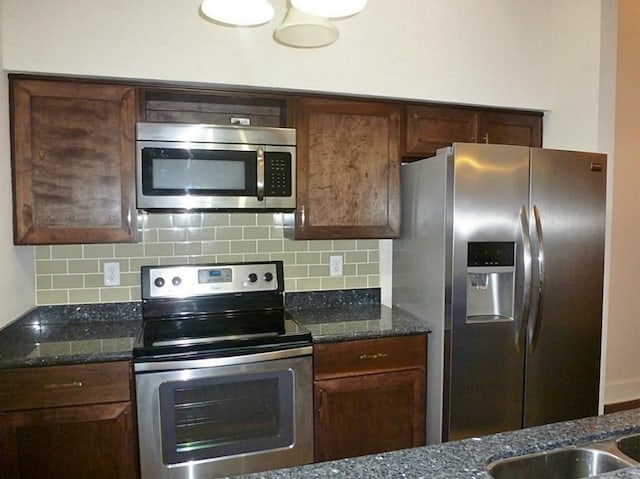 kitchen with tasteful backsplash, dark stone counters, and appliances with stainless steel finishes