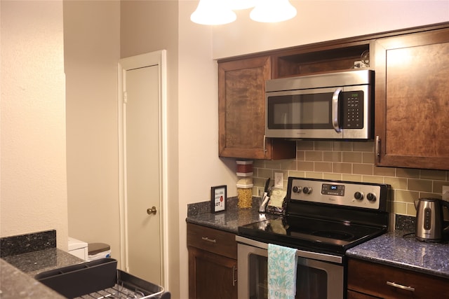 kitchen featuring dark stone countertops, dark brown cabinetry, backsplash, and appliances with stainless steel finishes