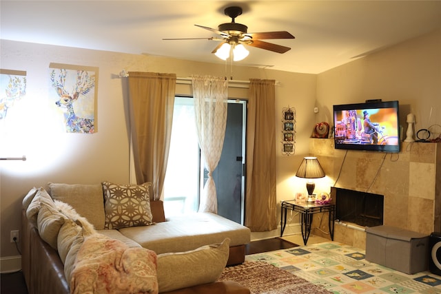 living room featuring a tiled fireplace and ceiling fan