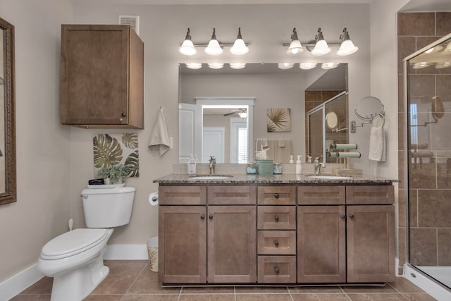 bathroom featuring a shower with shower door, toilet, double sink vanity, and tile patterned flooring