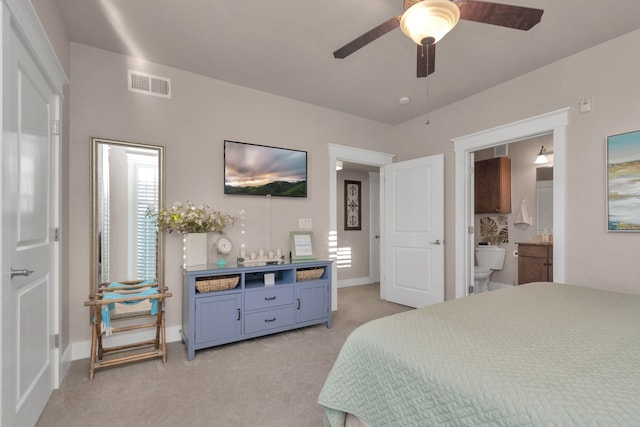 carpeted bedroom featuring multiple windows, ensuite bath, and ceiling fan