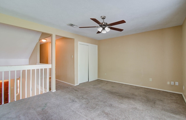 additional living space featuring a textured ceiling, lofted ceiling, ceiling fan, and carpet