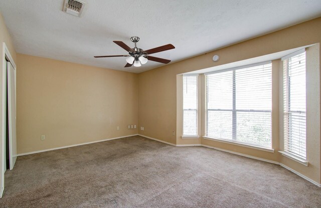 unfurnished room with a textured ceiling, plenty of natural light, ceiling fan, and carpet