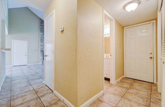 hallway with a textured ceiling and light tile patterned floors