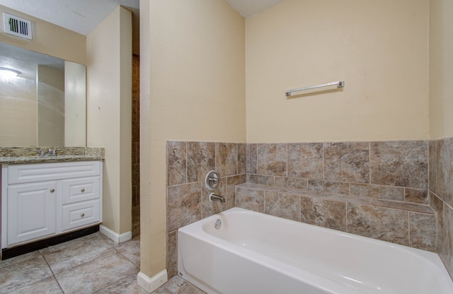 bathroom with vanity, a textured ceiling, tile patterned flooring, and a washtub