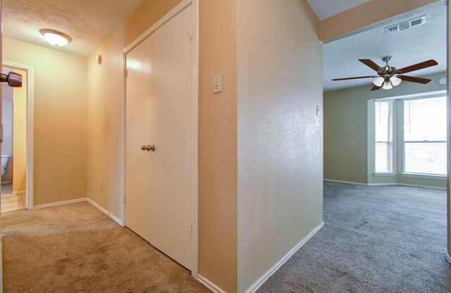 corridor featuring a textured ceiling, light colored carpet, and vaulted ceiling