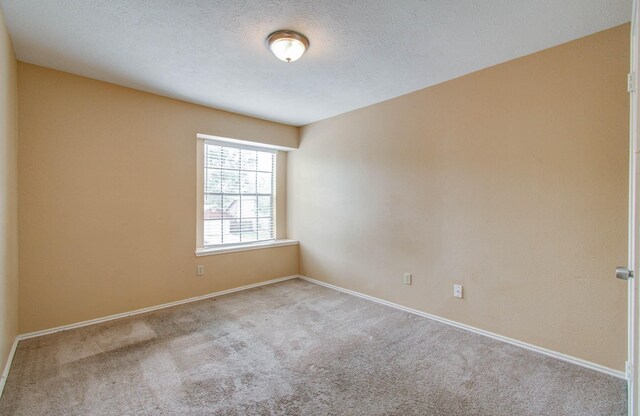 unfurnished room with a textured ceiling and carpet floors