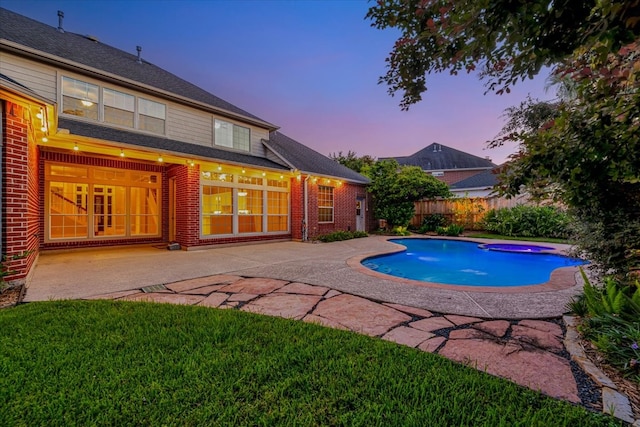 pool at dusk featuring a patio and a yard