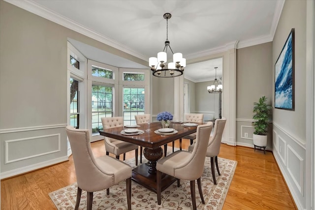 dining room with crown molding, light hardwood / wood-style floors, and a notable chandelier