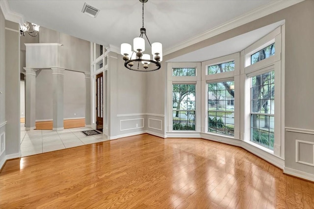 unfurnished dining area featuring an inviting chandelier, light hardwood / wood-style flooring, decorative columns, and a healthy amount of sunlight