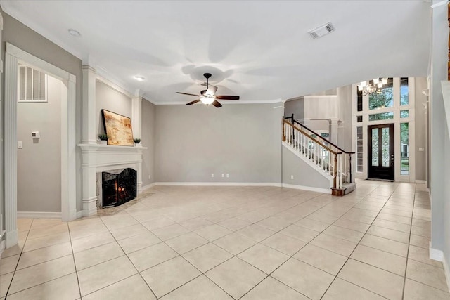 unfurnished living room with crown molding, ceiling fan with notable chandelier, light tile patterned floors, and a fireplace