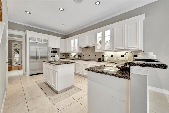 kitchen with white cabinets, dark stone counters, stainless steel built in fridge, and a kitchen island