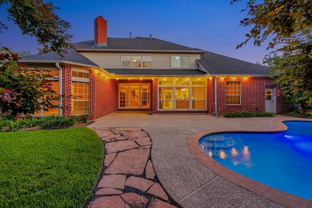 pool at dusk featuring a yard and a patio area