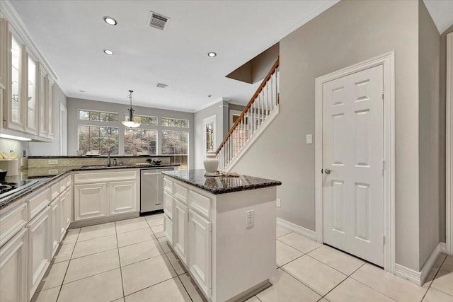 kitchen featuring white cabinetry, decorative light fixtures, stainless steel dishwasher, a kitchen island, and dark stone counters