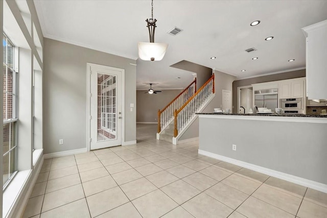 interior space with light tile patterned floors, a wealth of natural light, and ornamental molding