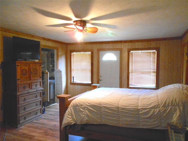 bedroom with hardwood / wood-style flooring, wood walls, and ceiling fan