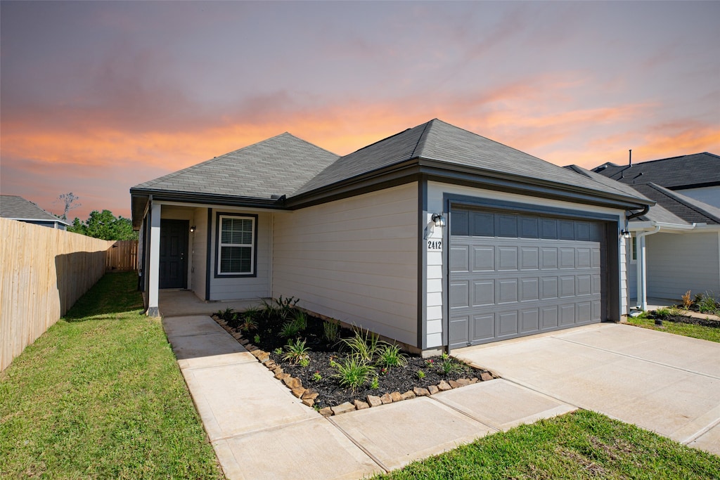 ranch-style home featuring a garage and a lawn