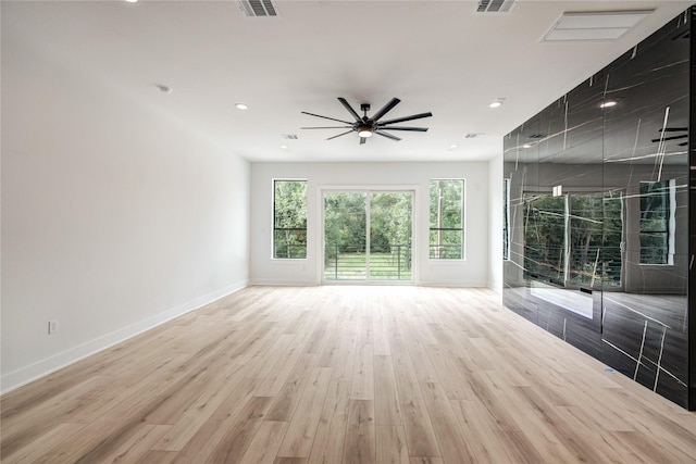 unfurnished living room featuring light hardwood / wood-style flooring, a wealth of natural light, and ceiling fan