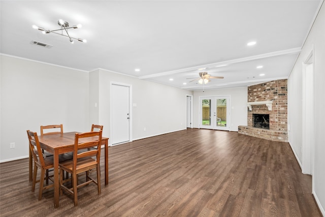 dining space with a fireplace, crown molding, dark hardwood / wood-style floors, brick wall, and ceiling fan