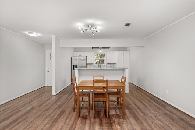 dining space featuring wood-type flooring, a notable chandelier, and ornamental molding