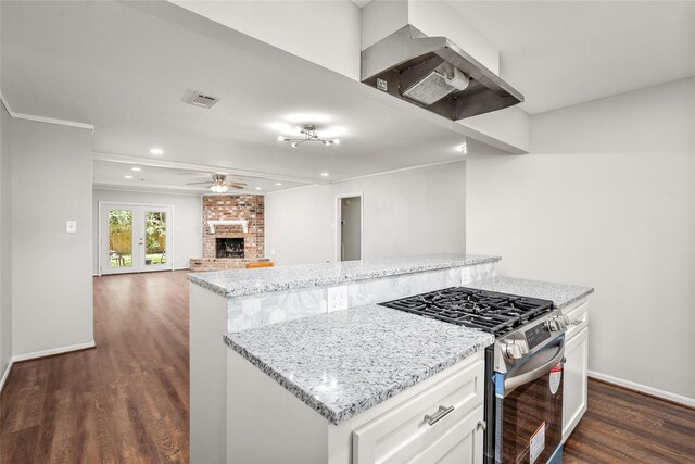 kitchen featuring white cabinets, a fireplace, gas stove, a center island, and dark wood-type flooring