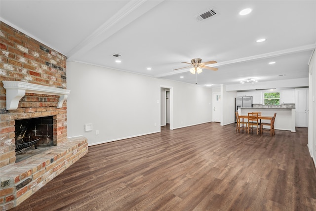 unfurnished living room featuring a fireplace, ceiling fan, dark hardwood / wood-style flooring, crown molding, and brick wall