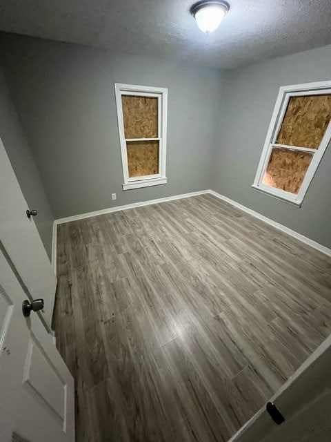 unfurnished room with a healthy amount of sunlight, hardwood / wood-style floors, and a textured ceiling