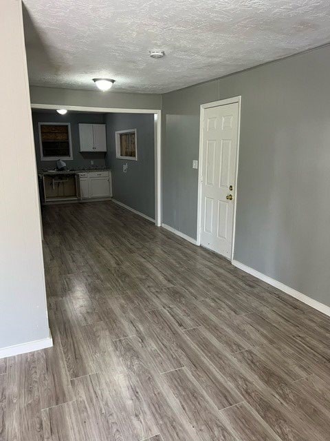 unfurnished living room with dark wood-type flooring and a textured ceiling