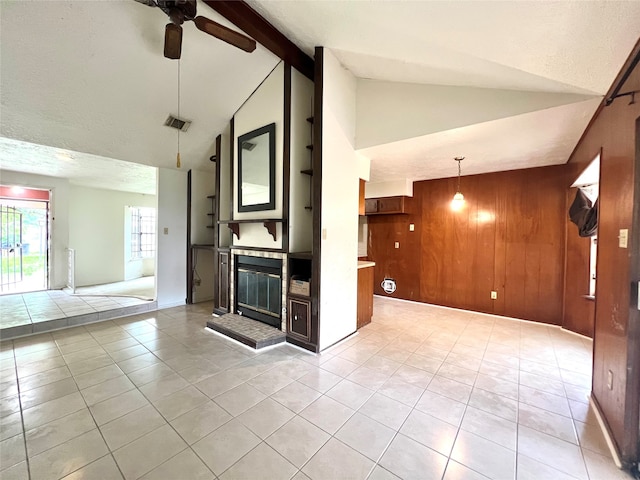 unfurnished living room with ceiling fan, wooden walls, high vaulted ceiling, and light tile patterned floors