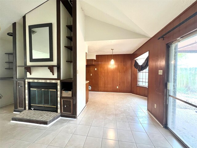 corridor featuring wood walls, lofted ceiling, and light tile patterned floors