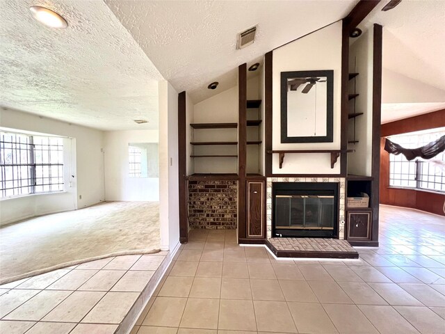 unfurnished living room with light tile patterned flooring, built in features, a textured ceiling, and lofted ceiling