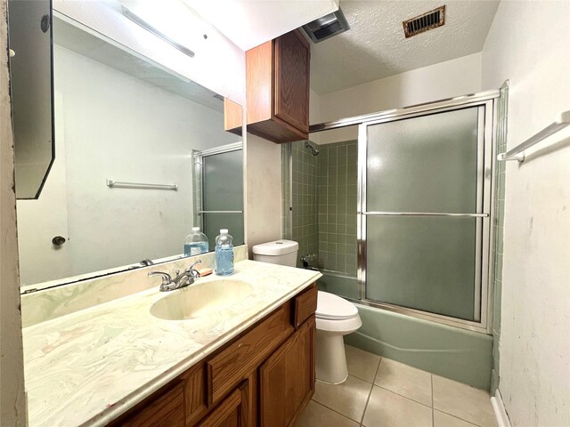 full bathroom with combined bath / shower with glass door, tile patterned flooring, a textured ceiling, toilet, and vanity