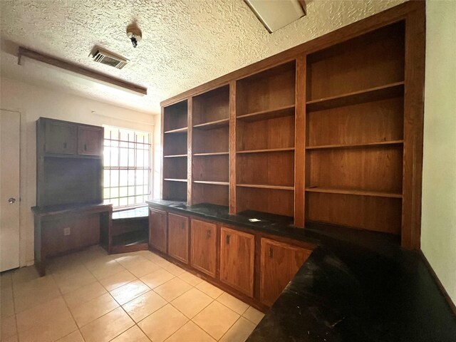 unfurnished office with a textured ceiling and light tile patterned floors