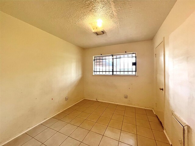 tiled empty room with a textured ceiling