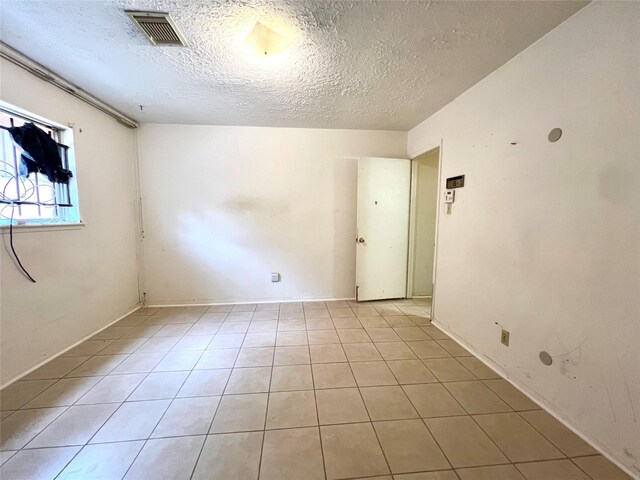 tiled empty room with a textured ceiling