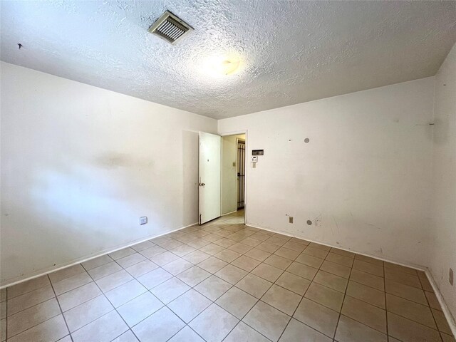 spare room featuring a textured ceiling and light tile patterned floors