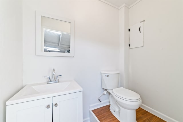 bathroom with hardwood / wood-style flooring, toilet, vanity, and ornamental molding