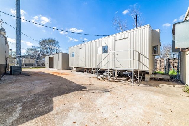 rear view of property featuring central air condition unit and a shed