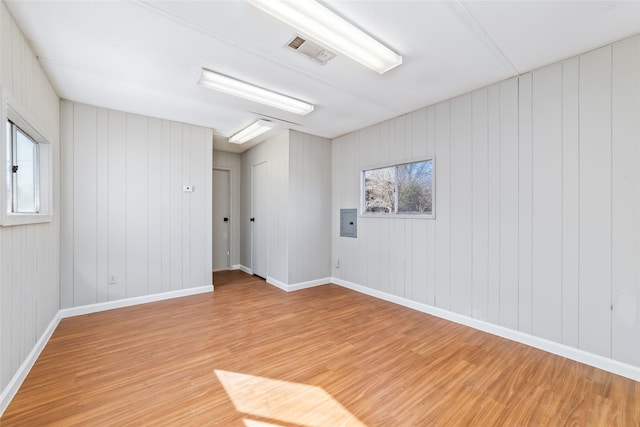 spare room featuring electric panel and light wood-type flooring