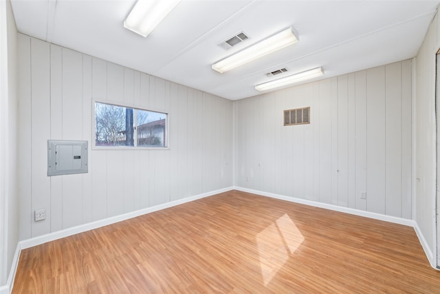 spare room featuring electric panel and hardwood / wood-style floors